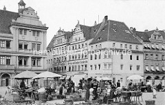 Historische Geschäfts- und Wohngebäude am Markt von Torgau. Marktstände mit Körben, Gemüse - Marktverkäuferinnen; Fassadenaufschrift Herren- und Knaben Garderobe,