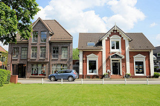 Wohnhäuser / Geschäftshäuser in der Kirchstraße von Hittfeld; historischer Altbau, moderner Neubau mit Dachgiebel.