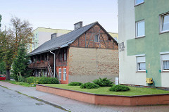 Historische Wohnhaus mit Fachwerk und Laubengang zwischen Beton-Wohnblocks in Toruń.