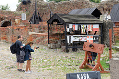 Souvenirladen und gebührenpflichtiger Eingang zur Ordensburg in Torun - ein Kind steht für ein Foto der Eltern am Pranger.