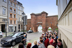 Historische Stadtbefestigung von Toruń - Stadtmauer mit Stadttor / Segeltor. Touristengruppe beim Sightseeing / Stadtführung vor dem Pałac Dąmbskich.