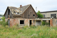 Altes verlassenes Ziegelgebäude mit Holzfassade, Giebelverkleidung - hohes Wildkraut / Unkraut an der Bahnhofstraße von Belgern.