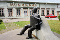 In Pärnu wurde 1838 das erste städtische Kurbad eröffnet; das historische Kurhaus / Kursaal wurde im Stil der Kurarchitektur 1893 errichtet. Bronzekulptur Akkordeonspieler; Fassadenschild Kuursaal.