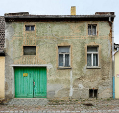 Wohnhaus mit Tor in der Pfarrstraße von Belgern; abgebröckelter Putz - Reste von  Fassadendekor.