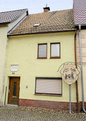 Schmales Wohnhaus aus dem 17. Jahrhundert in Schildau - Schild der Geschichte der Schildbürger mit dem Maushund.