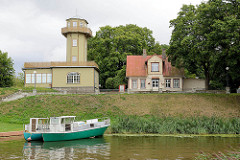 Leuchtturm, Leuchtfeuer am Fluss Pärnu; Holzhaus des Leuchtturmwärters, Ausflugsboot am Ufer.
