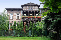 Fachwerkvilla mit Holzbalkon und Ziergiebel - blühende Geranien; Architektur in Toruń.