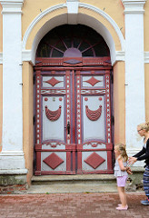 Doppeltür / Holztür mit farbigen Schnitzelementen - historisches Gebäude in Pärnu, Estland.