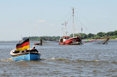 Ein Tuckerboot / Holzboot fährt mit großer Deutschlandfahne elbaufwärts - der Fischkutter HBK 103 hat seine Netze ausgelegt. Der Kutter Luise wurde 1950 gebaut und hat eine Länge von 16 m.