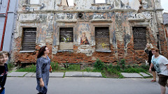 Alte Hausfassade, Hausruine mit vernagelten Fenstern und Graffiti / Stencil in Kaunas.