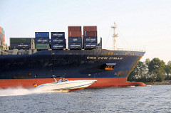 Die im Jahr 2005 gebaute CMA CGM Otello hat eine Länge von 335m und eine Breite von fast 43 m. Das Schiff kann 8488 Standardcontainer transportieren. Ein schnelles Sportboot überholt das Frachtschiff auf der Elbe.