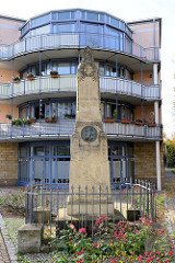Moderne halbrunde Hausfassade mit umlaufenden Balkons; Stele  für den Maler Paul Emil Jacobs - 1867 errichtetes Denkmal für den Gothaer Bürger.