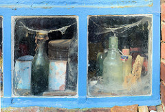Scheunenfenster / Eisenfenster eines Schuppens in Seestermühe - Spinnweben und alte Flaschen.