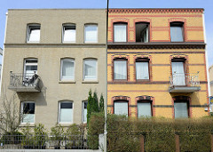 Symmetrische Architektur in der Straße Steenwisch von Hamburg Stellingen; das Gebäude rechts  hat die alte gelbe Klinkerfassade  mit roten Zierbändern, während die linke Fassade  eintönig modernisiert wurde.
