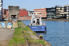 Alte Gleise an der Südseite vom Alten Hafen in Münster - auf der Nordseite die Neubauten vom Kreativkai; das Boot "Münster" der Wasserschutzpolizei hat am Kai festgemacht.
