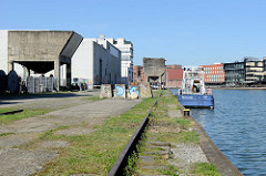 Alte Gleise und Schüttgutanlage an der Südseite vom Alten Hafen in Münster - auf der Nordseite die Neubauten vom Kreativkai; das Boot "Münster" der Wasserschutzpolizei hat am Kai festgemacht.