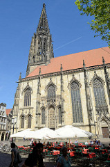 Lamberti Kirche in Münster, erbaut zwischen 1375 und 1525; Aussengastronomie mit Tischen unter Sonnenschirmen auf dem Kirchplatz / Salzstraße.