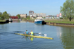 Ruderboot auf dem Dortmund-Ems-Kanal in Münster - Hafenbecken mit Sportbooten und Brachland.