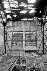 Ruine eines Lokschuppens - das Dach ist verfallen, mit großen Löchern - Fenster sind vernagelt.