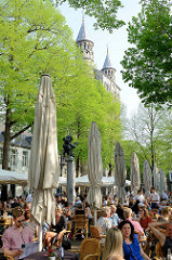 Straßencafé unter Bäumen auf dem Onze Lieve Vrouweplein in Maastricht - im Hintergrund Spitzen der Kirchtüme von der Liebfrauenbasilika.
