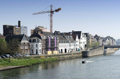 Wohnhäuser am Ufer der Maas Maastricht, ein Motorboot fährt flussaufwärts.