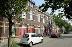 Einstöckiger  Wohnblock - geschlossene  Straßenbebauung mit roter Backsteinfassade und gelben  Zierbändern in der Van Den Berghstraat in Maastricht.