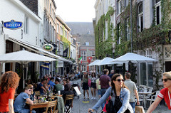 Fussgängerzone in der Koestraat  von Maastricht - Gäste von Cafés und Restaurant sitzen an Tischen auf der Straße.