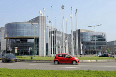 Moderne Bürogebäude  mit Glasfront - Kreisverkehr  vor dem Verwaltungsgebäude von Limburg in Maastricht - die europäischen Sterne sind auf langen Stangen in der Platzmitte aufgespießt / Europa Denkmal zur Einführung der Eurowährung in der EU.