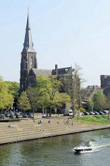 Blick von der Wilhelminabrug über die Maas zur katholischen        Sint Martinuskerk / St. Martinskirche; am Flussufer laden Terrassen zum Sitzen in der Sonne ein.