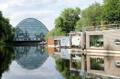 Moderne, neue Hausboote liegen am Ufer des Hochwasserbassins in Hamburg Hammerbrook; im Hintergrund das Bürogebäude Berliner Bogen.
