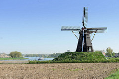 Windmühle am Ufer der Maas auf dem Weg nach Roermond - ein Binnenschiff fährt flussabwärts.