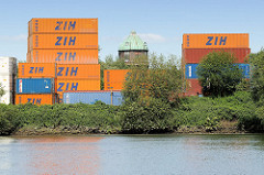 Blick über den Schmidtkanal in Hamburg Wilhelmsburg zu einem Containerlager am Kanalufer - dazwischen die Kupferkuppel vom Wilhelmsburger Wasserturm.