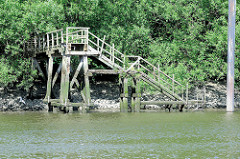 Verlassene Holztreppe im Hafen Hamburgs / Hafenbecken Moldauhafen;  der Zugang ist mit Gebüsch zugewachsen, die Holzkonstruktion ist bei Niedrigwasser freigelegt und gut zu erkennen.