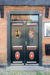 Alte, dunkelgrüne Holztür mit ovalen Fenstern - rote Schnitzerei / rot gefasst; Skolegade von Ribe.