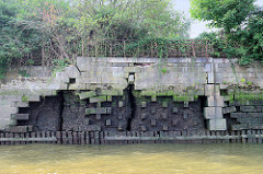Kaimauer am Moldauhafen im Kleinen Grasbook; das Niedrigwasser legt das Holzfundament und Reste einer Ziegelmauer frei - in breite Risse kann Wasser eindringen. Lks. eine Treppe zum Wasser - oben ein altes Eisengeländer.