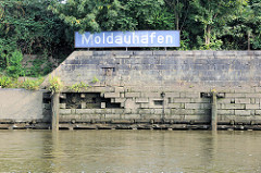 Kaimauer bei Niedrigwasser - blaues Schild Moldauhafen im Hamburger Stadtteil Kleiner Grasbrook.