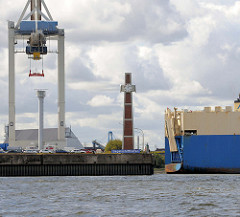 Blick zum Pegelturm auf dem Amerikahöft im Hamburger Hafen - davor ein altes blaues Schild, das auf das Hafenbecken Segelschiffhafen hinweist. Heck eines RoRo Schiffs beim Hansahafen.