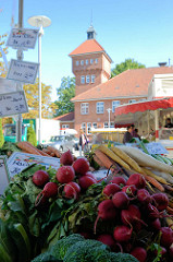 Marktstand mit Gemüse / Radischen auf dem Wochenmarkt in Hamburg Alsterdorf - im Hintergrund das historische Küchengebäude der Alsterdorfer Anstalten, das unter Denkmalschutz steht.