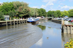Blick auf die Krückau im Elmshorner Hafen bei Ebbe - das Hafenbecken ist größtenteils trockengefallen. Im Hintergrund das Binnenmotorfrachtschiff Klostersande, das  zwischen 1968 und 2000 für die Köllnflockenwerke  Getreide zwischen dem Hamburger Haf