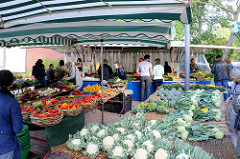 Marktstand mit frischem Gemüse auf dem Wochenmarkt Tibarg im Hamburger Stadtteil Niendorf. Blumenkohl, Kohlrabi und Brokkoli sind auf einem Tisch ausgebreitet, verschiedene Paprikasorten liegen in  Weidenkörben.