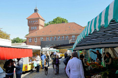 Markttreiben / Marktstände  auf dem Alsterdorfer Marktplatz im Hamburger Stadtteil Alsterdorf. Im Hintergrund das historische Küchengebäude der Alsterdorfer Anstalten, das unter Denkmalschutz steht.