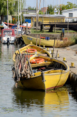 Fischereihafen in in Ziegenort / Trzebież; kleine Holzboote liegen am Kai des Hafenbeckens.