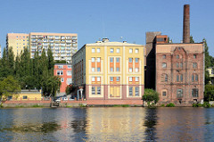 Alte Lagerhäuser am Ufer der Westoder in Stettin, im Hintergrund Hochhäuser.