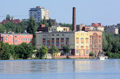 Alte Lagerhäuser am Ufer der Westoder in Stettin, im Hintergrund Hochhäuser.