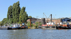 Blick über den Reiherstieg zur Einfahrt in den Grevenhofkanal in Hamburg Steinwerder; Arbeitsboote und Werfgebäude der M. A. Flint Werft.