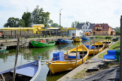 Fischereihafen in in Ziegenort / Trzebież; kleine Holzboote liegen am Kai des Hafenbeckens - im Hintergrund sind Fischernetze zum Trocknen aufgehängt.