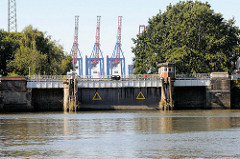 Blick über den Grevenhofkanal zu Grevenhofschleuse in Hamburg Steinwerder; im Hintergrund die Containerkräne vom Waltershofer Hafen / Containerterminal Burchardkai.