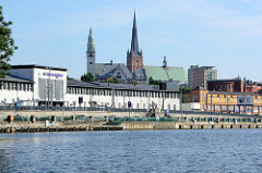 Blick von der Oder  auf das Bahnhofsgebäude / Empfangsgebäude Szczecin Główny. Dahinter historische und moderne Gebäude sowie die St. Jakobi-Kathedrale und dem Turm vom Rektorat der Pommerschen Medizinischen Universität Stettin.