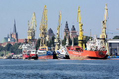 Blick von der Westoder auf die Hafenanlagen von Stettin - Frachtschiffe und Kräne; im Hintergrund die historischen Türme der alten Hansestadt.