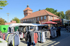 Marktstand mit Kleidung auf dem Wochenmarkt in Hamburg Alsterdorf - im Hintergrund das historische Küchengebäude der Alsterdorfer Anstalten, das unter Denkmalschutz steht.